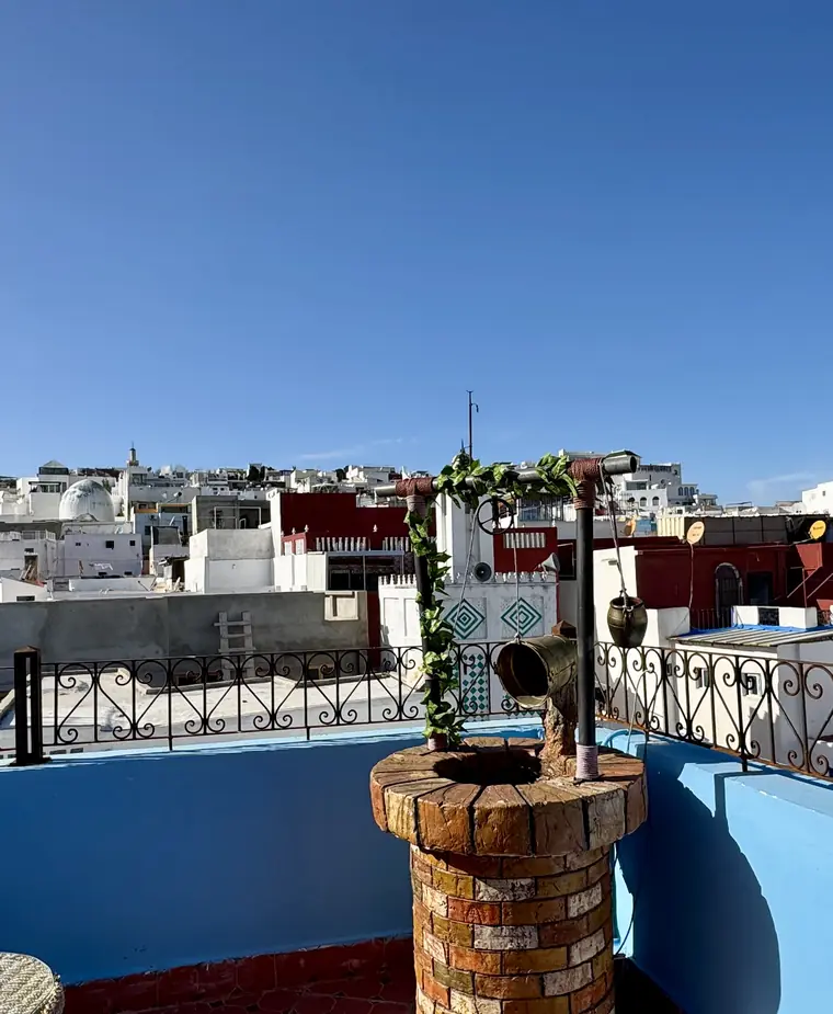 Notre terrasse sur le toit : muret bleu, garde-corps en fer forgé et les toits de Tanger au fond